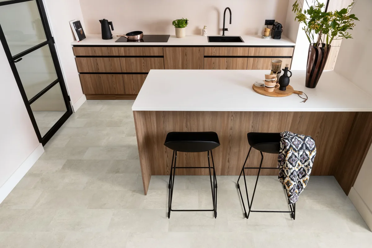 Madison Square Aqua / Expression Aqua grijsbruin, tegellaminaat met natuursteenlook in een keuken met een houten kookeiland en zwarte barkrukken