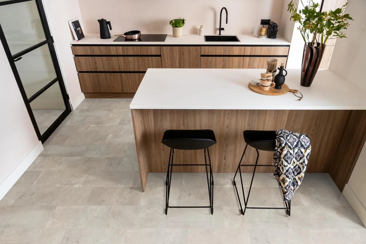 Madison Square Aqua / Expression Aqua zand, tegellaminaat met natuursteenlook in een keuken met een houten kookeiland en zwarte barkrukken