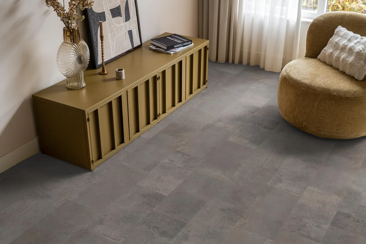 Madison Square Aqua / Expression Aqua grijs, tegellaminaat met natuursteenlook in een woonkamer met een okergeel dressoir en een ronde fauteuil
