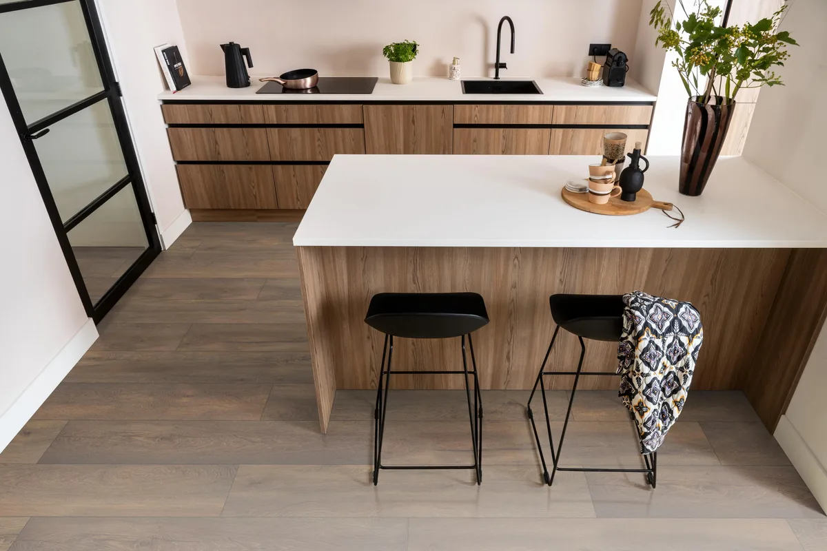 Union Square / Saarland donkerbruin eiken, laminaat in een keuken met een houten kookeiland en zwarte barkrukken