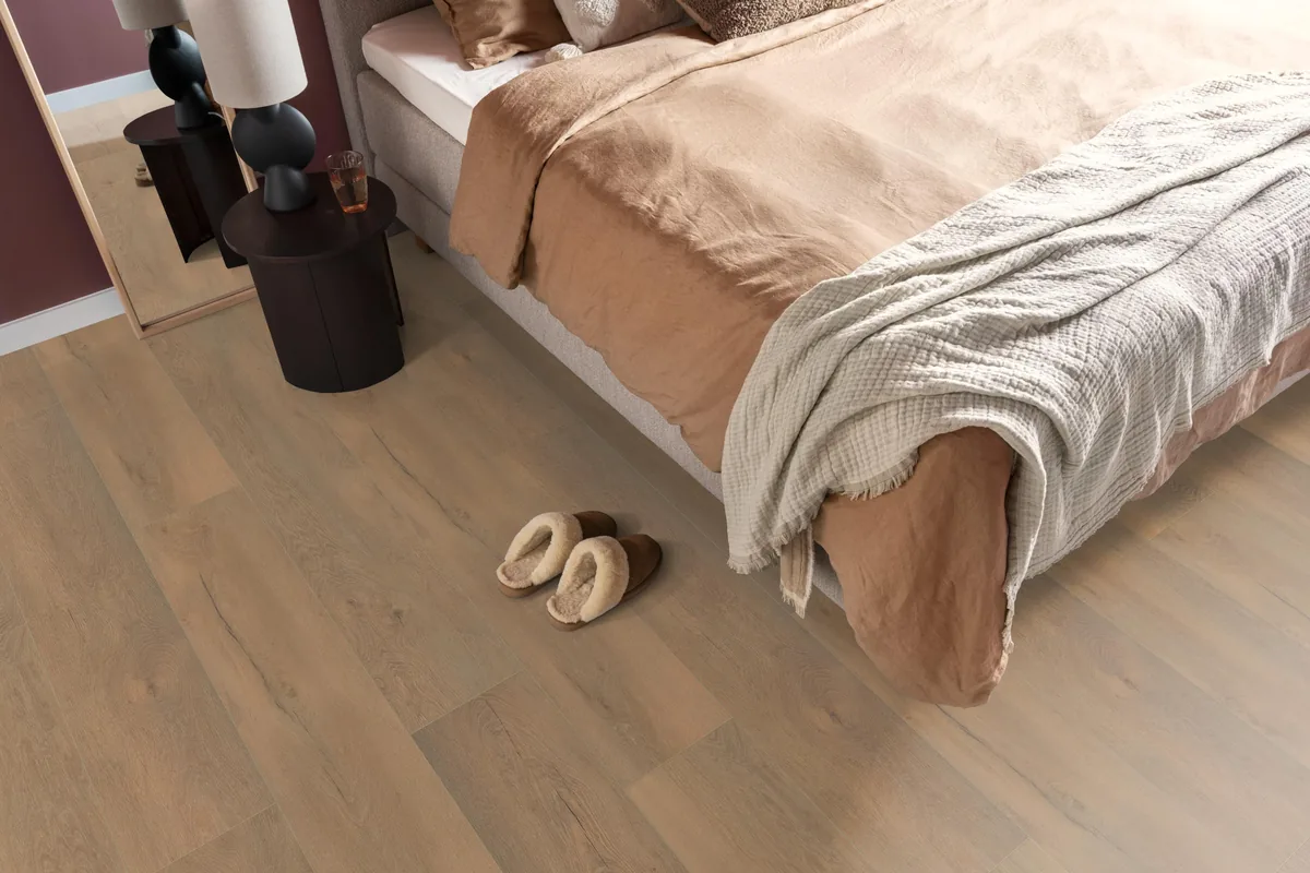 Union Square / Saarland natuur eiken, laminaat in een slaapkamer, met sloffen naast het bed en een donker nachtkastje