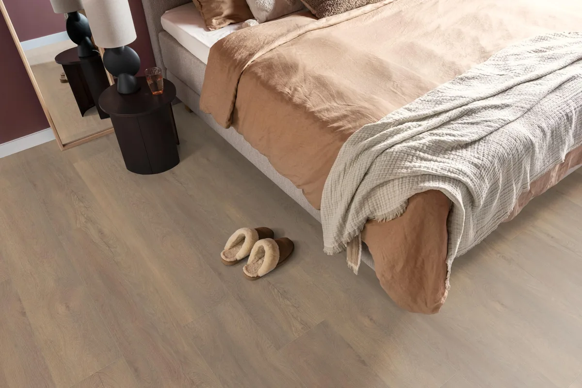 Union Square / Saarland smoky eiken, laminaat in een slaapkamer, met sloffen naast het bed en een donker nachtkastje