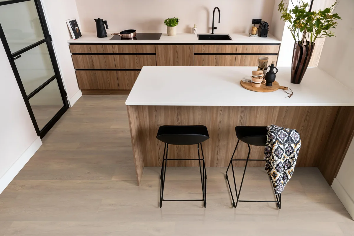 Union Square / Saarland smoky eiken, laminaat in een keuken met een houten kookeiland en zwarte barkrukken