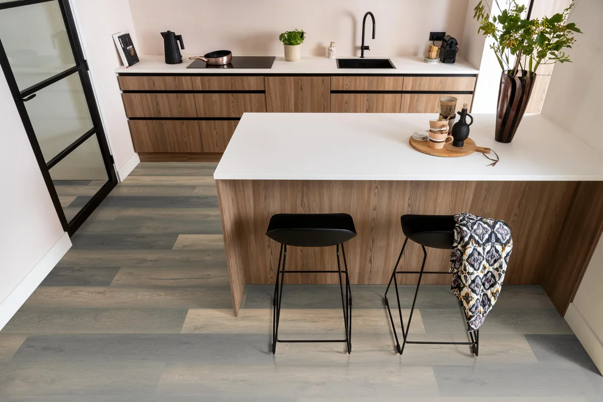 Midwood / Saksen titan eiken, laminaat in een keuken met een houten kookeiland en zwarte barkrukken