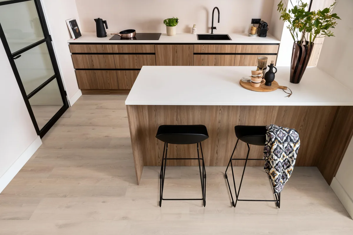 Inwood WR / Ingelstad blond eiken, laminaat in een keuken met een houten kookeiland en zwarte barkrukken