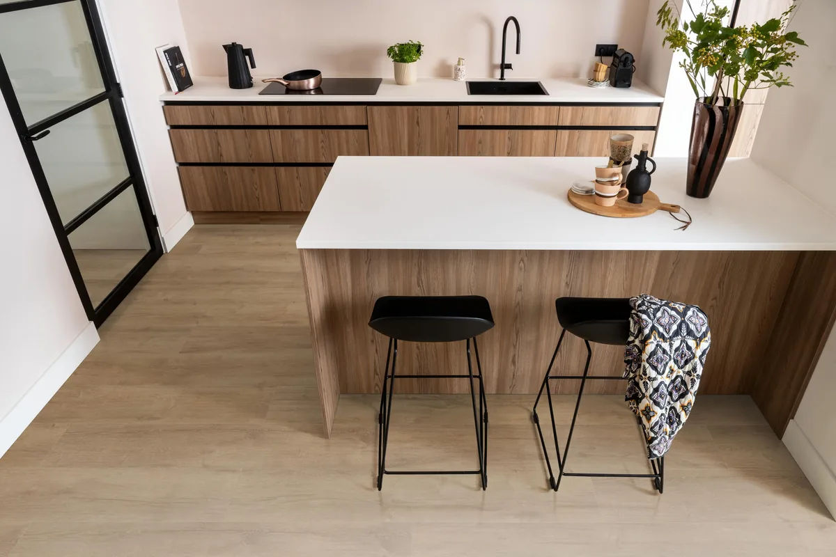 Sunnyside / Superior oak lichtbruin eiken, laminaat in een keuken met een houten kookeiland en zwarte barkrukken