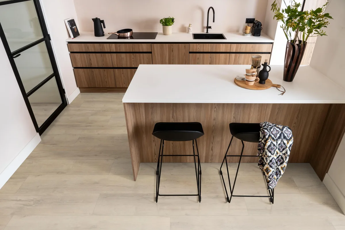 Sunnyside / Superior oak beige eiken, laminaat in een keuken met een houten kookeiland en zwarte barkrukken