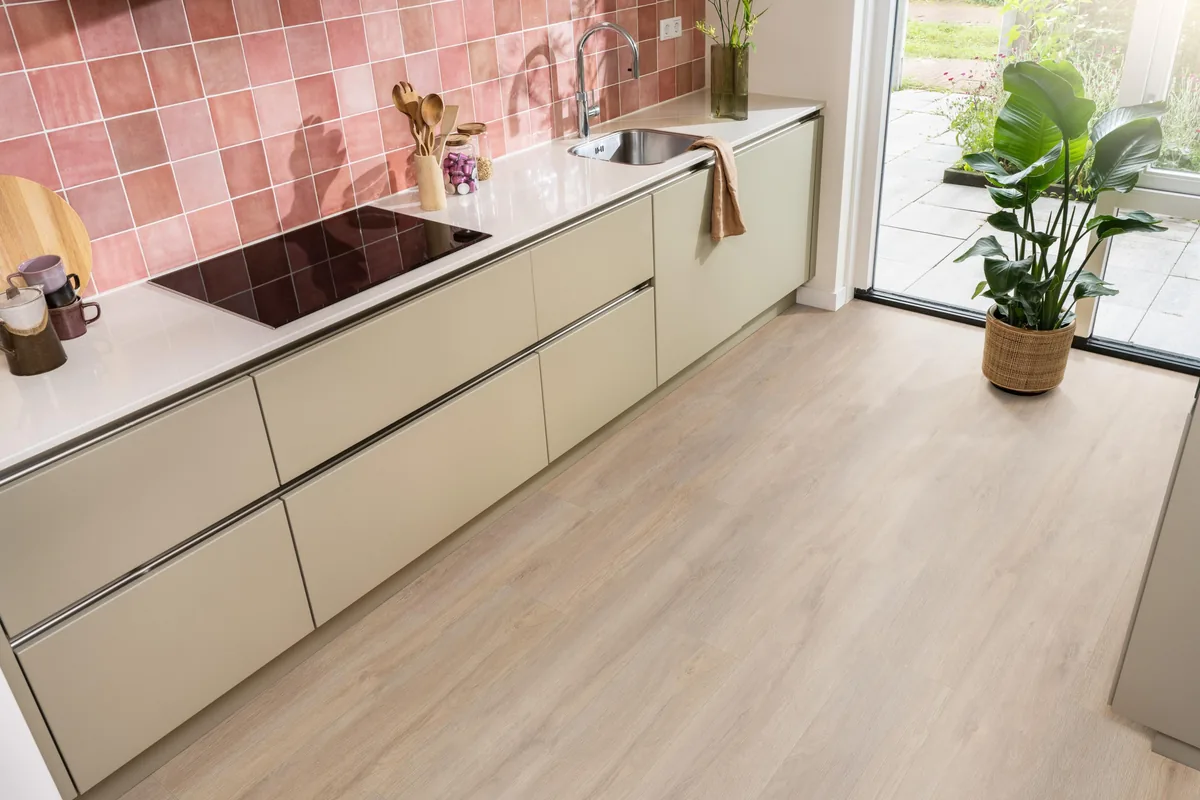 Norwood / Prestige oak warm eiken, laminaat in een keuken met roze tegelwand en openslaande tuindeuren