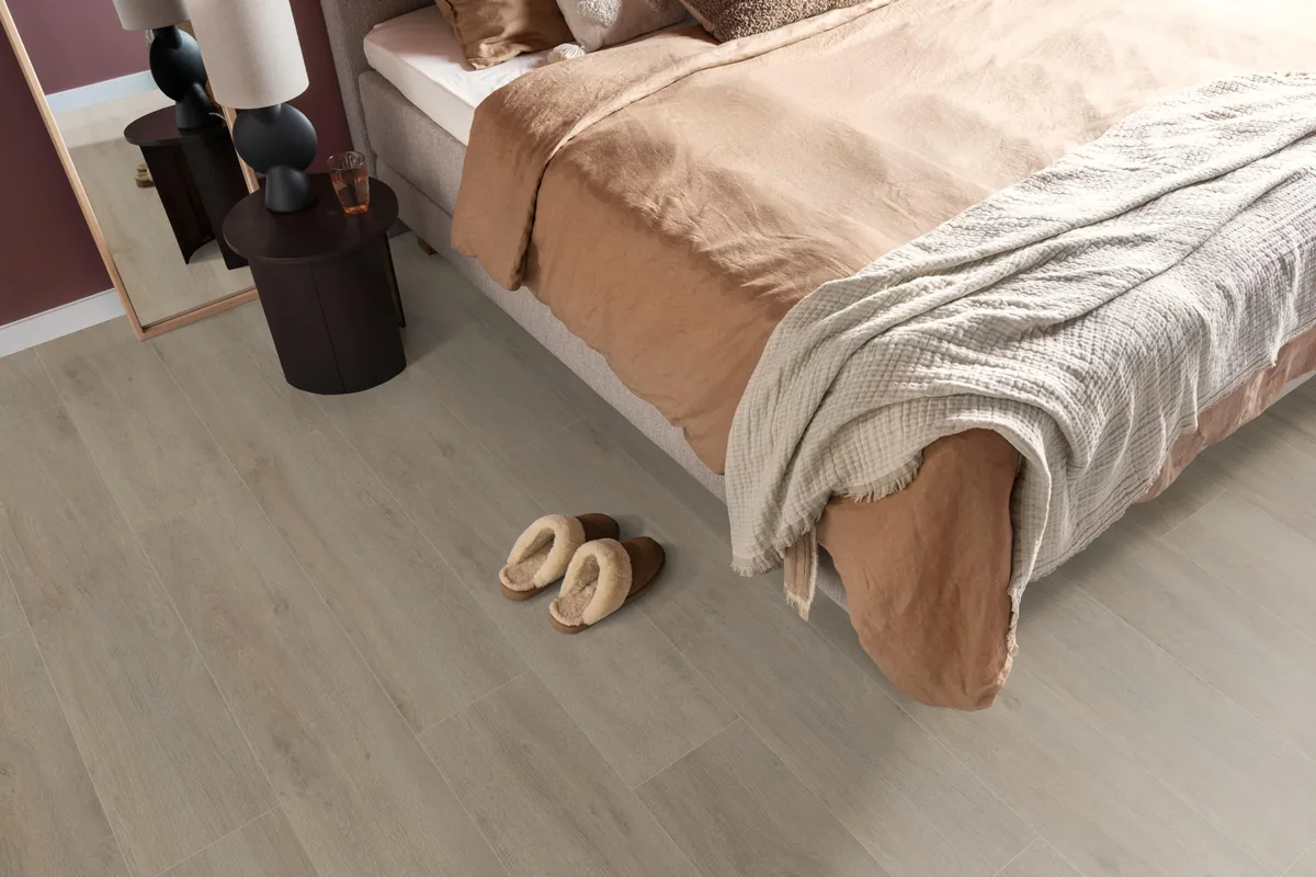 Norwood / Prestige oak grijsbruin eiken, laminaat in een slaapkamer, met sloffen naast het bed en een donker nachtkastje