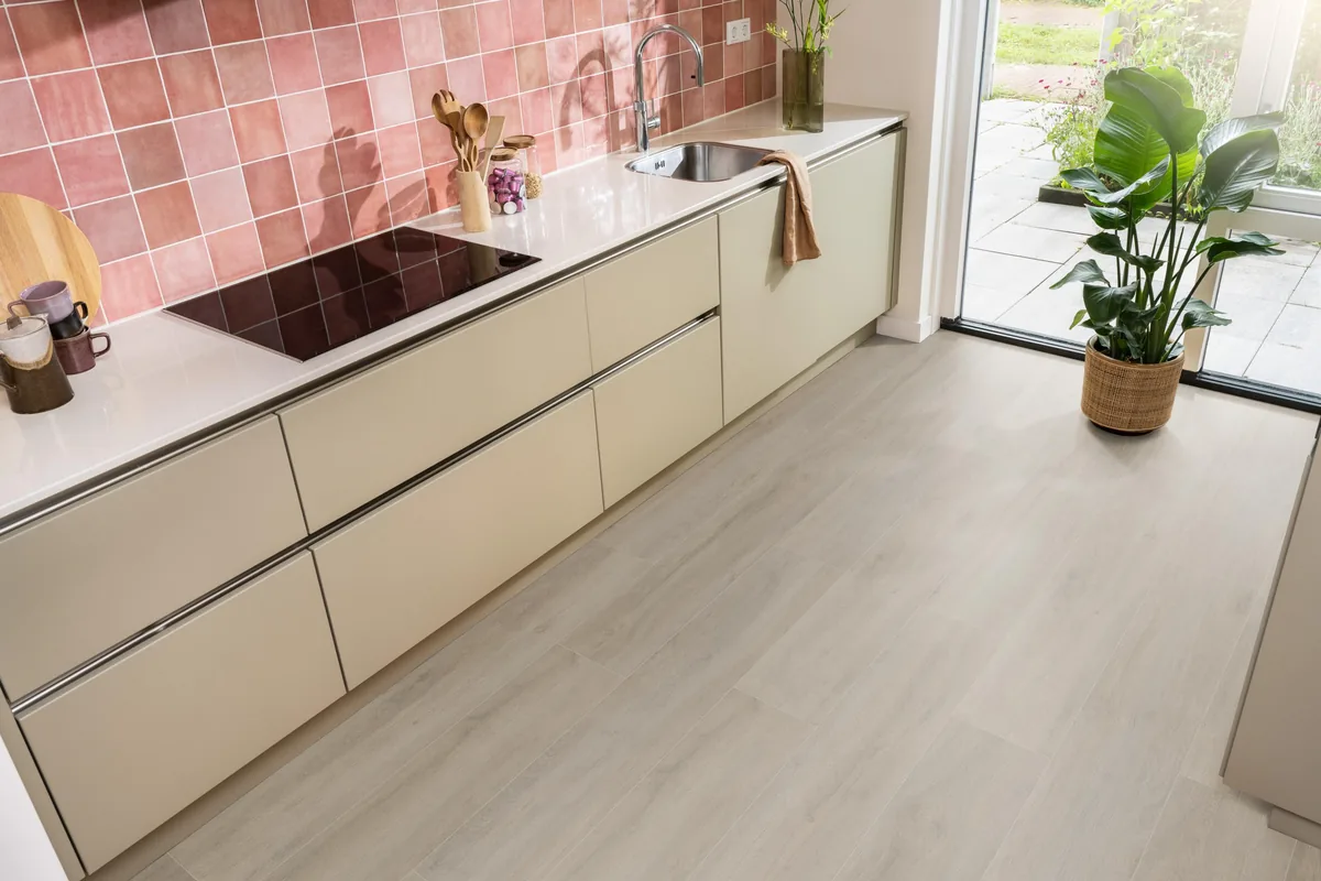 Norwood / Prestige oak grijsbruin eiken, laminaat in een keuken met roze tegelwand en openslaande tuindeuren