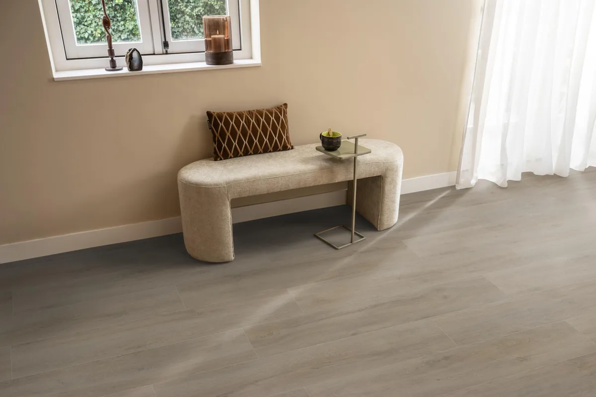 Norwood / Prestige oak grijsbruin eiken, laminaat in een hal, met een bankje onder het raam en zonlicht over de vloer