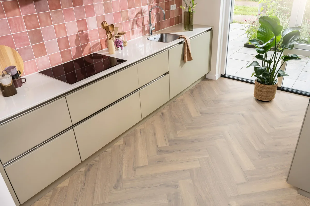 Bayside / Marquant eiken natuur, visgraat laminaat in een keuken met roze tegelwand en openslaande tuindeuren