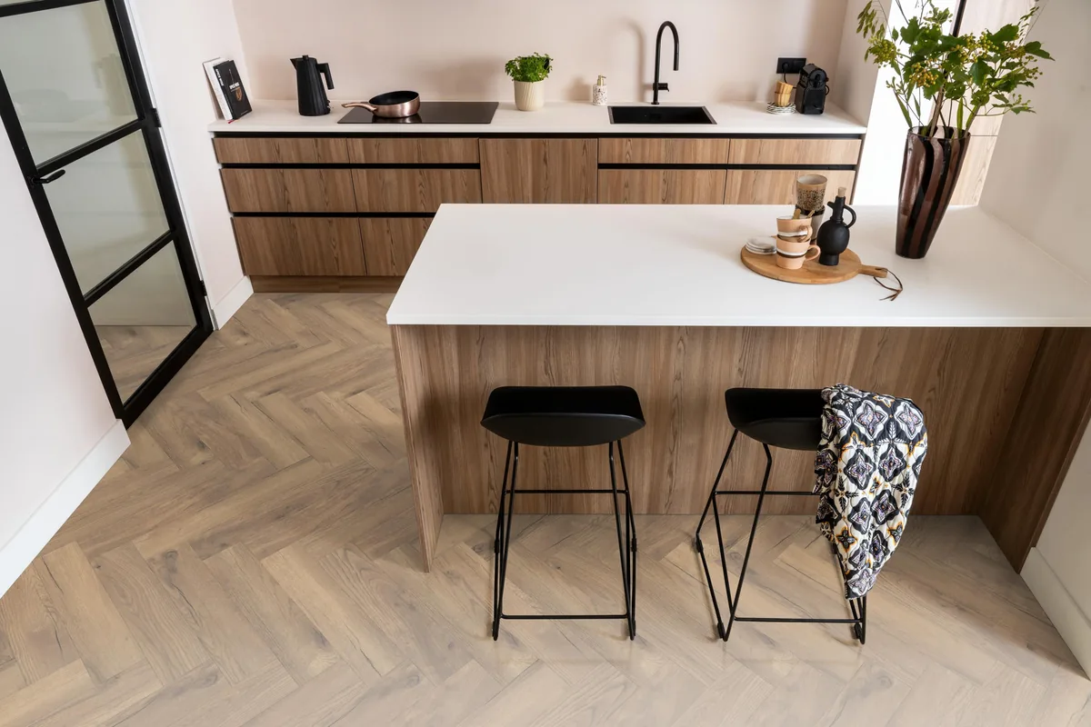 Bayside / Marquant eiken natuur, visgraat laminaat in een keuken met een houten kookeiland en zwarte barkrukken