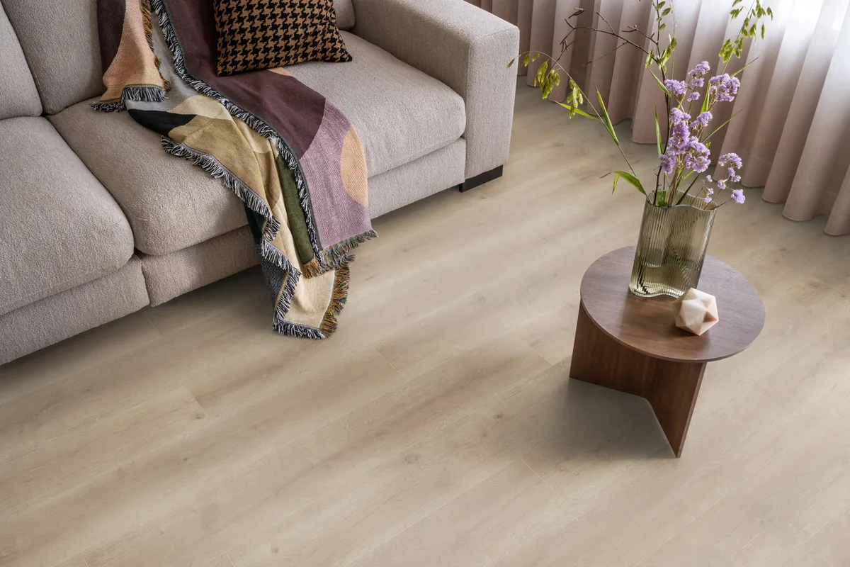 Queens / Elite naturel eiken, laminaat in een woonkamer met een lichte bank en een houten bijzettafel