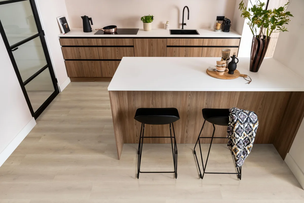 Queens / Elite naturel eiken, laminaat in een keuken met een houten kookeiland en zwarte barkrukken