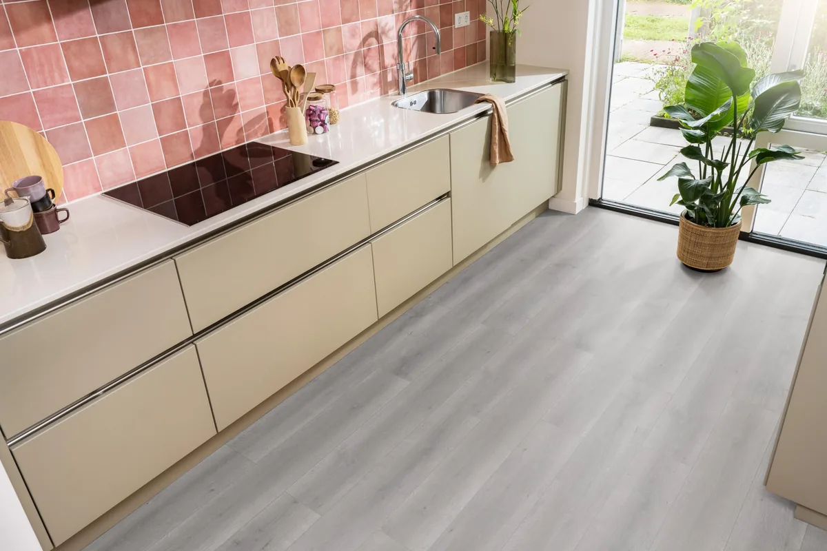 Queens / Elite grijs eiken, laminaat in een keuken met roze tegelwand en openslaande tuindeuren