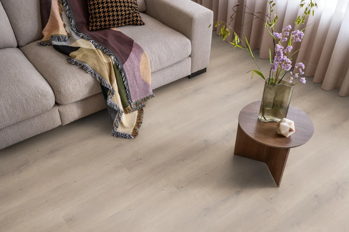 Queens / Elite beige eiken, laminaat in een woonkamer met een lichte bank en een houten bijzettafel