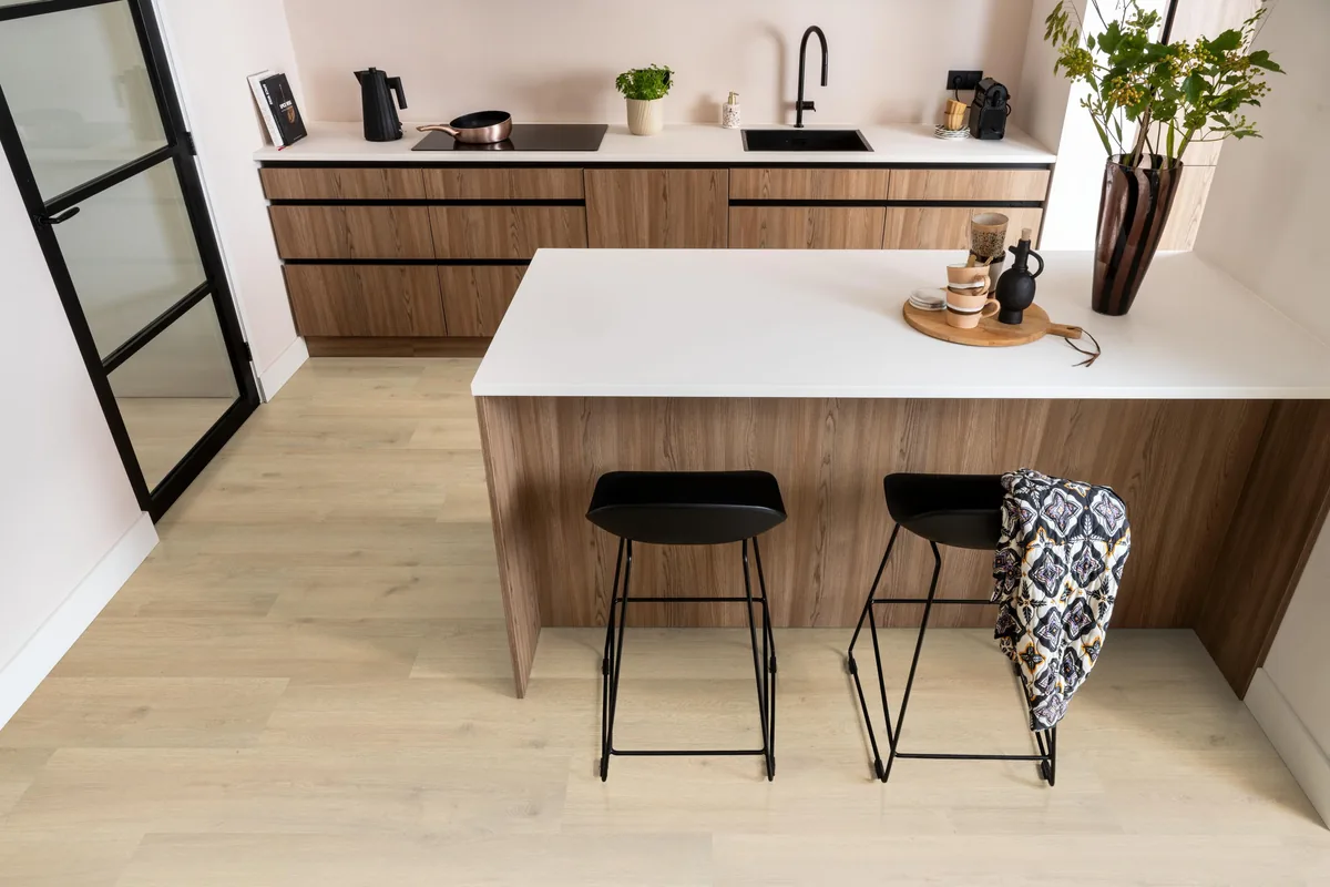 Forest Hills / Aachen beige eiken, laminaat in een keuken met een houten kookeiland en zwarte barkrukken
