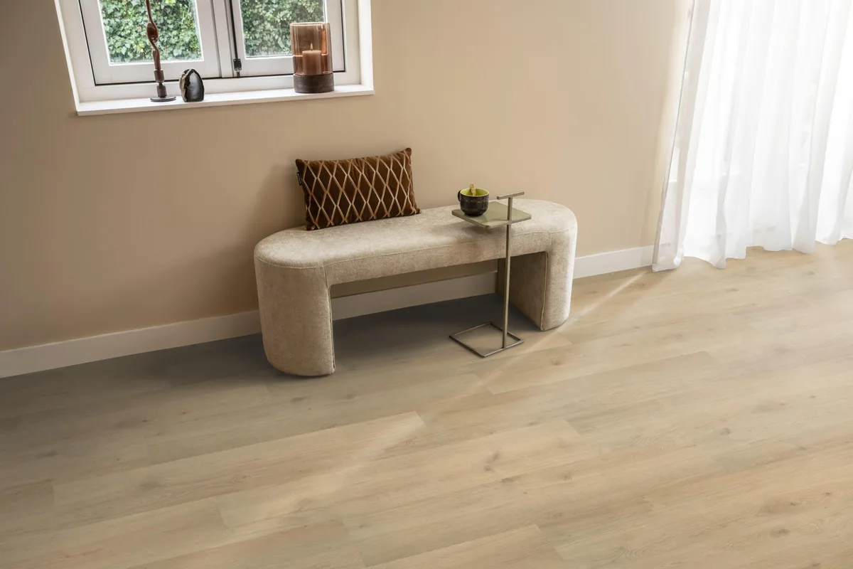 Forest Hills / Aachen beige eiken, laminaat in een hal, met een bankje onder het raam en zonlicht over de vloer