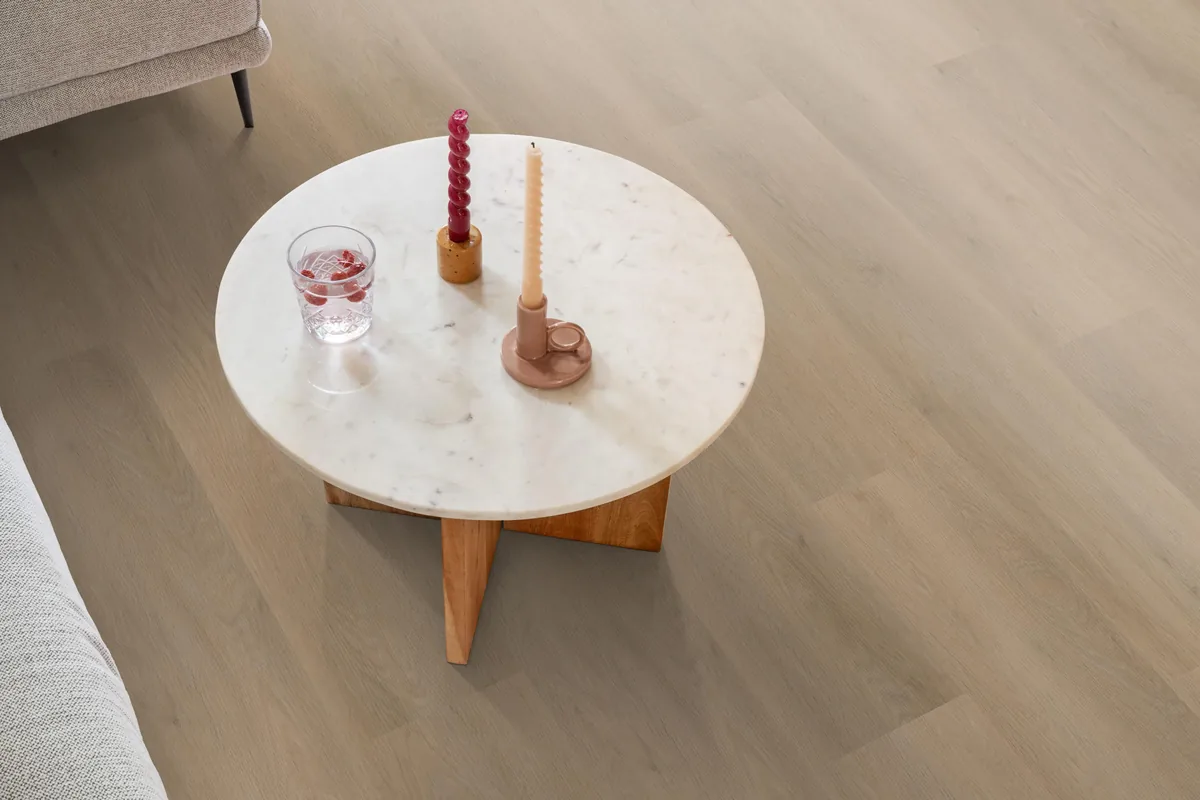 Newham / Sentima Beige, klik pvc in een woonkamer, met een ronde marmeren salontafel en twee kaarsen