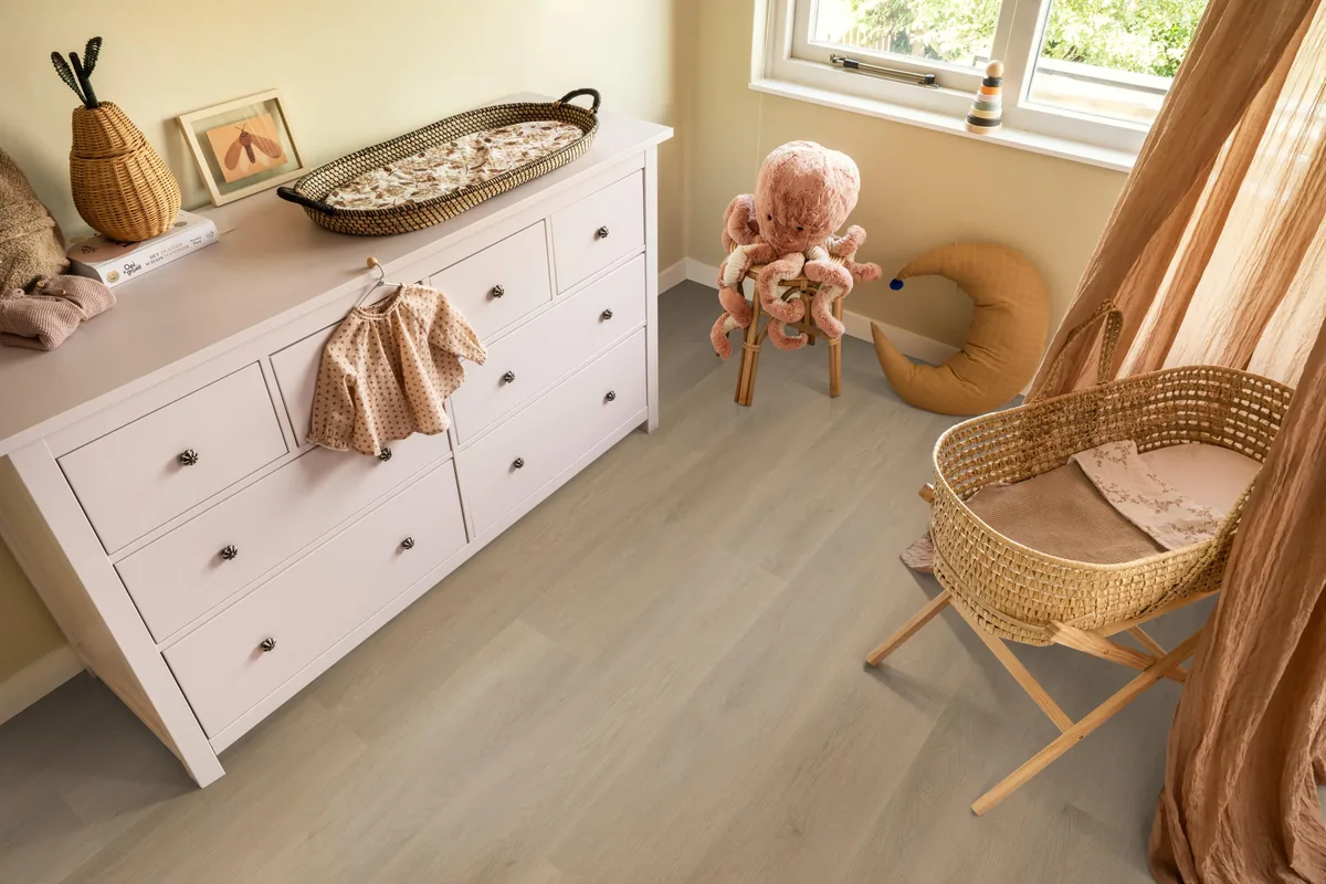Newham / Sentima Beige, klik pvc in een babykamer, met een witte commode en een rieten wieg