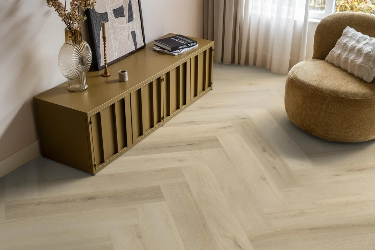 Greenford / Valento Warm beige, visgraat plak pvc in een woonkamer, met een okergeel dressoir en een ronde fauteuil