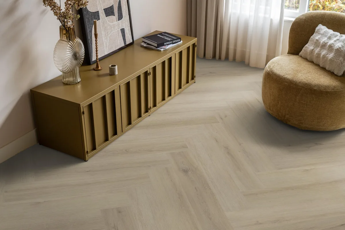 Greenford / Valento Beige, visgraat plak pvc in een woonkamer, met een okergeel dressoir en een ronde fauteuil