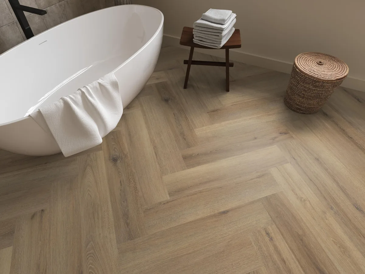 Greenford / Valento Light brown, visgraat klik pvc in een badkamer, met een vrijstaand bad en een rieten wasmand