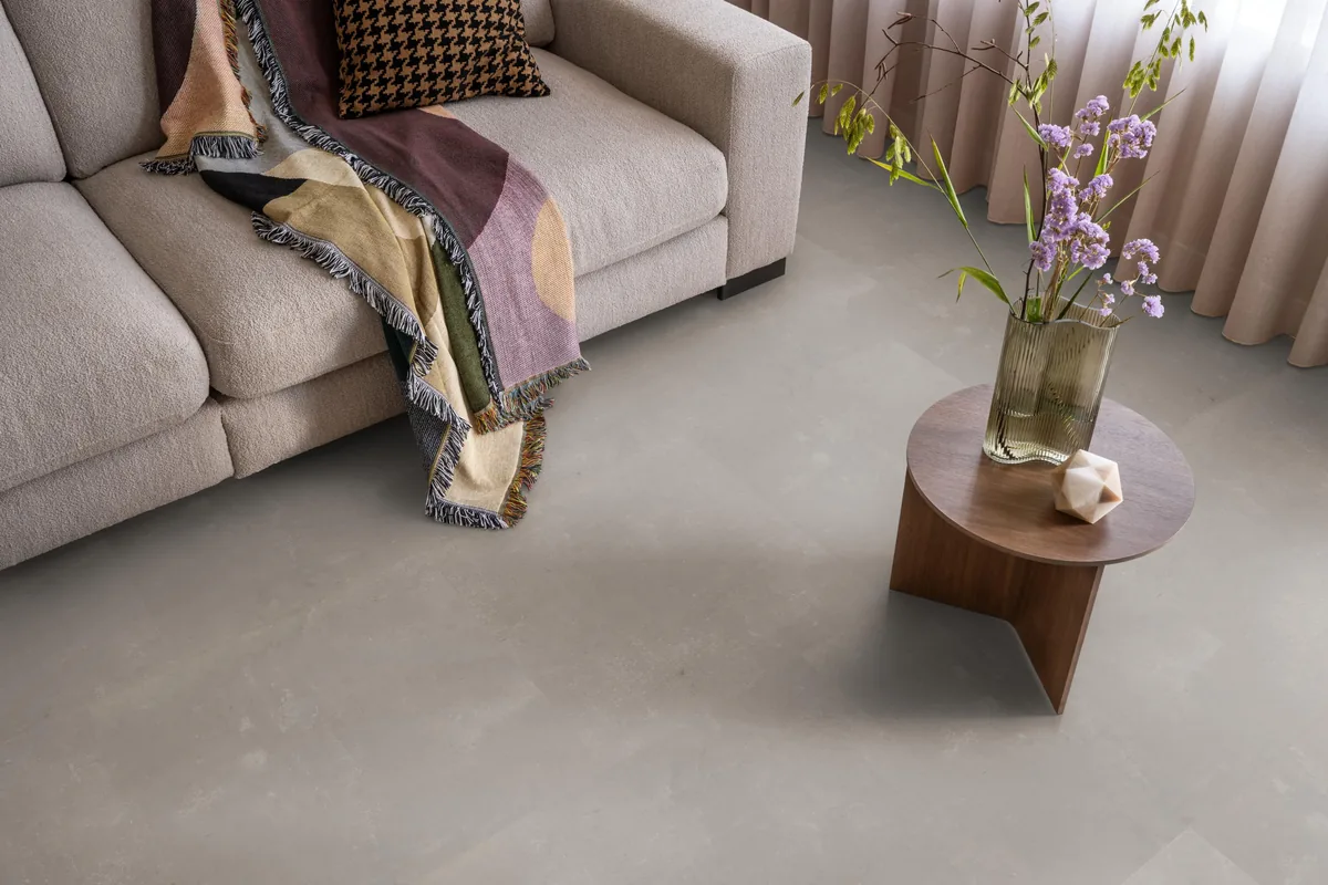 Westminster / Piero taupe, plak pvc in een woonkamer, met een beige bank en een ronde bijzettafel met bloemen