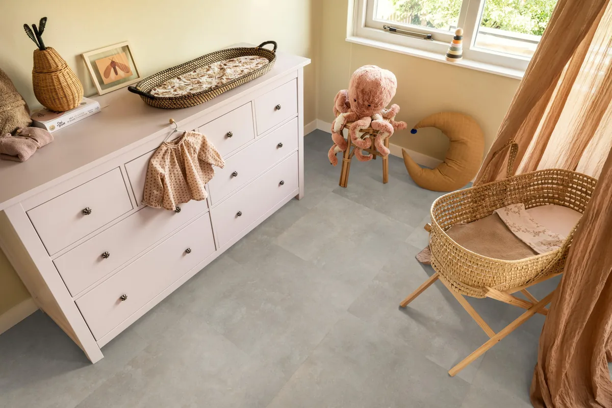 Victoria / Ceramo beige, plak pvc in een babykamer, met een witte commode en een rieten wieg