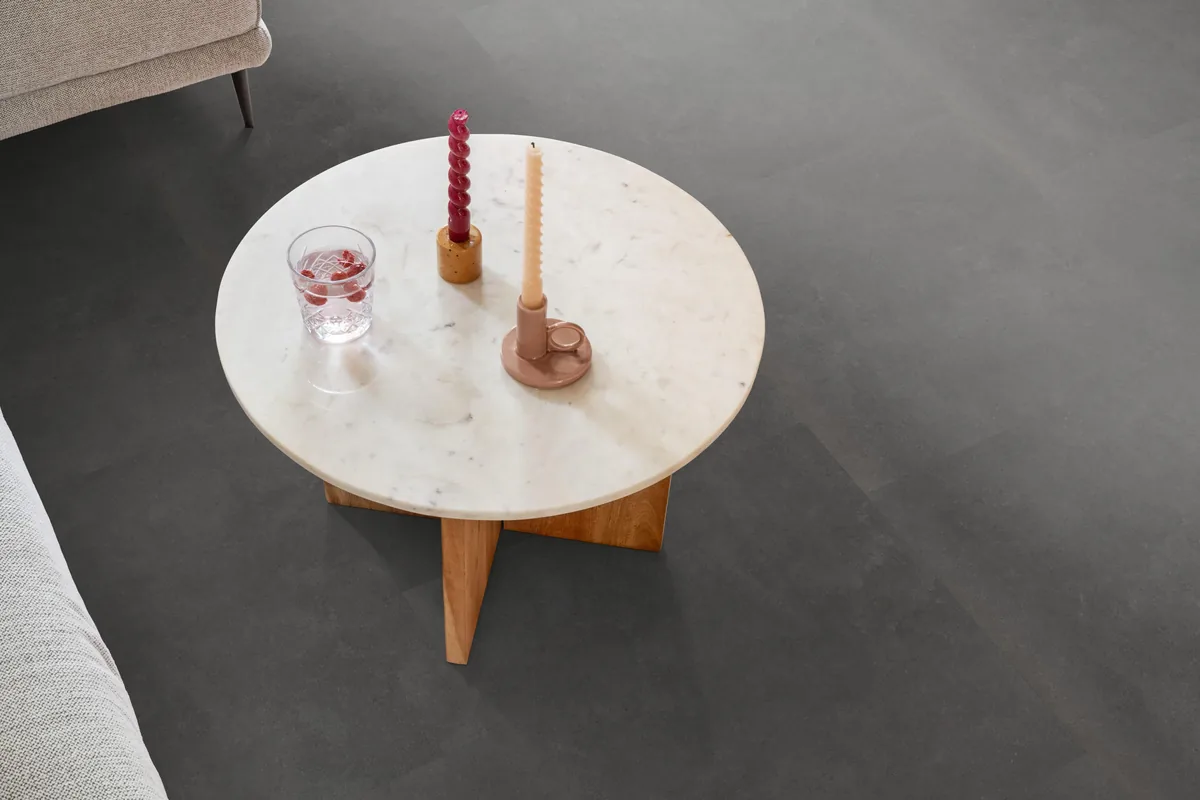 Victoria / Ceramo anthracite, plak pvc in een woonkamer, met een ronde marmeren salontafel en twee kaarsen