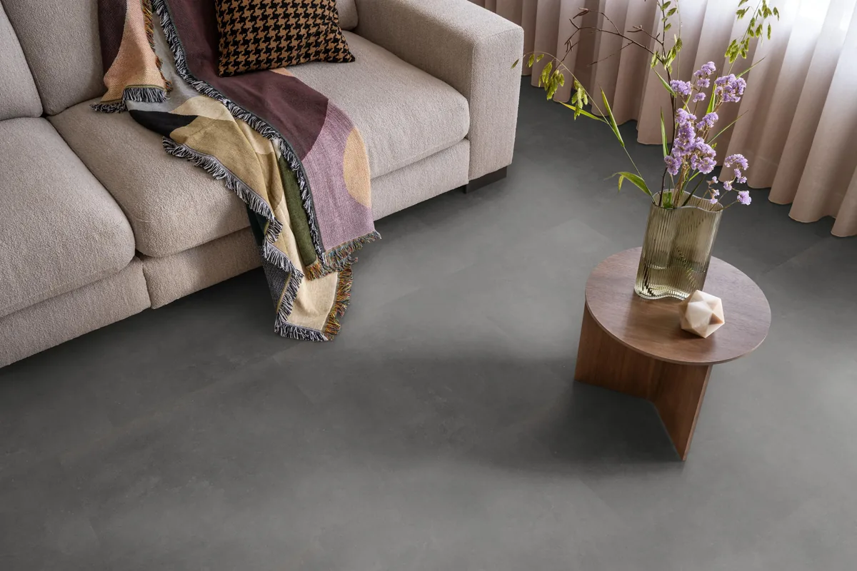 Victoria / Ceramo anthracite, plak pvc in een woonkamer, met een beige bank en een ronde bijzettafel met bloemen