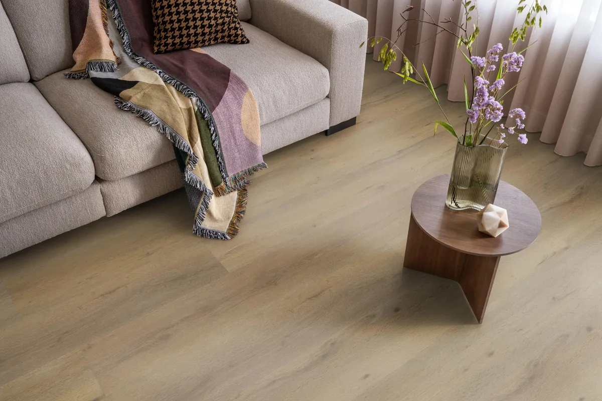 Leyton / Vivero dark oak, plak pvc in een woonkamer, met een beige bank en een ronde bijzettafel met bloemen