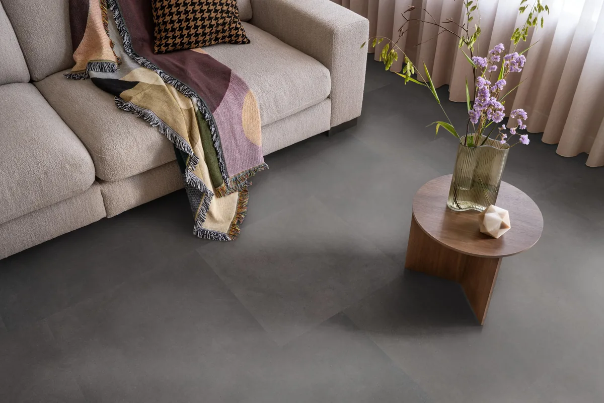 Peckham / Baroso anthracite, plak pvc in een woonkamer, met een beige bank en een ronde bijzettafel met bloemen