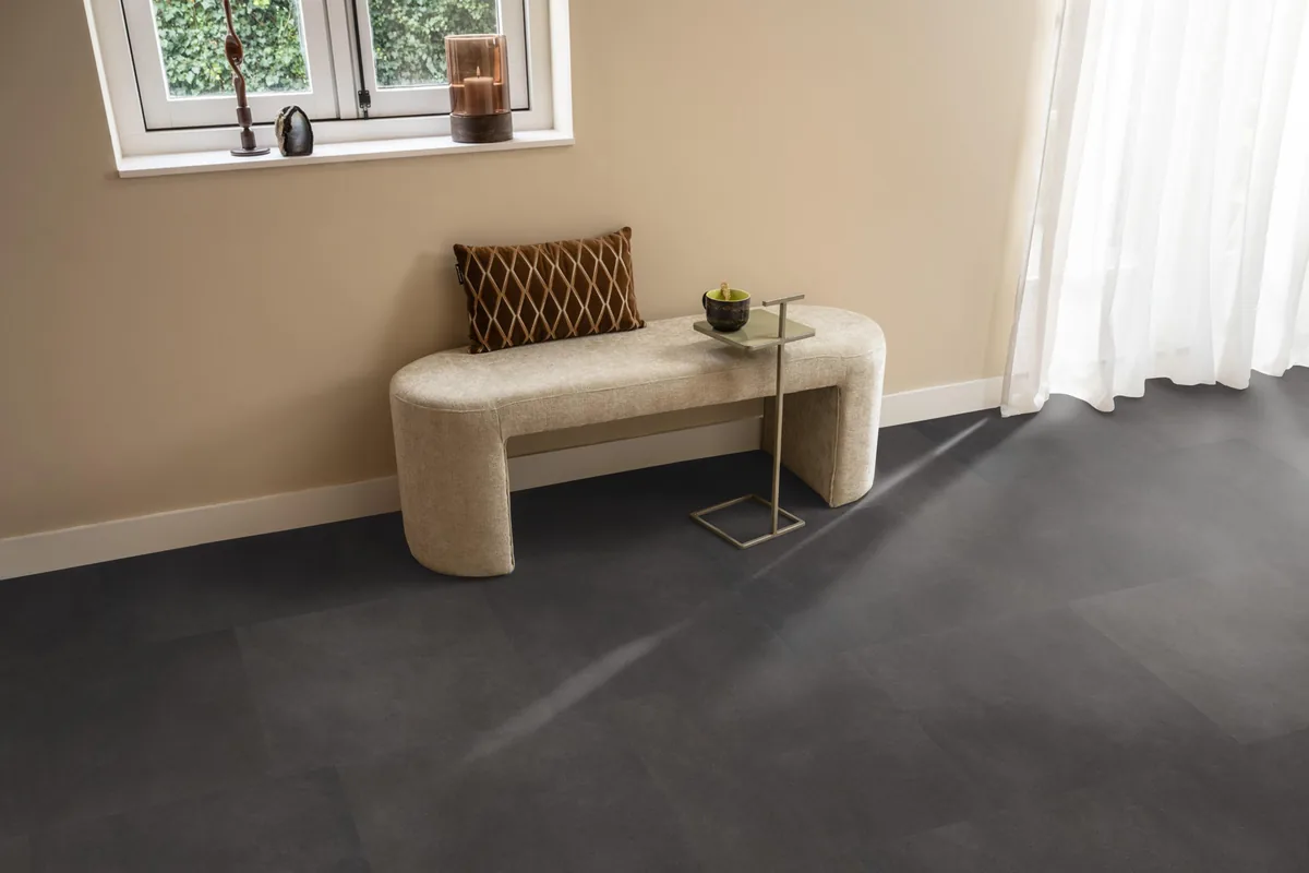 Peckham / Baroso anthracite, plak pvc in een hal, met een bankje onder het raam en zonlicht over de vloer