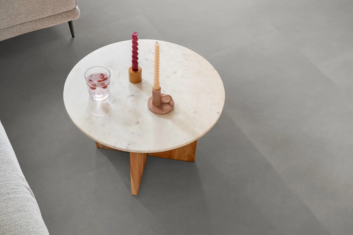 Peckham / Baroso grey, klik pvc in een woonkamer, met een ronde marmeren salontafel en twee kaarsen