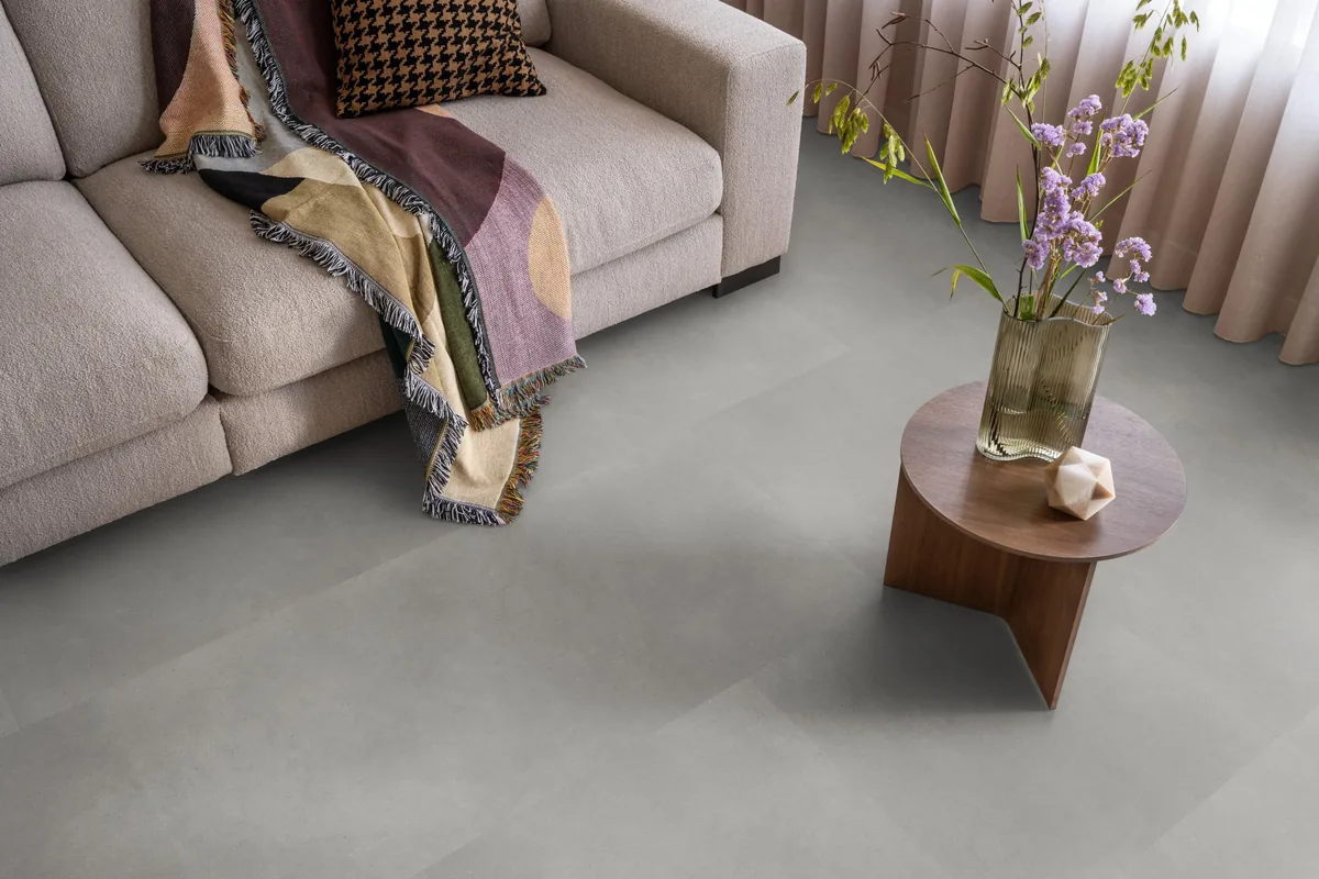 Peckham / Baroso grey, klik pvc in een woonkamer, met een beige bank en een ronde bijzettafel met bloemen