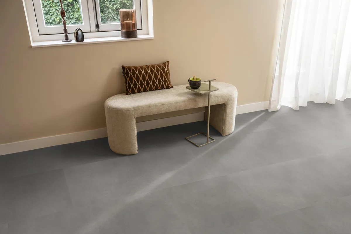 Peckham / Baroso grey, klik pvc in een hal, met een bankje onder het raam en zonlicht over de vloer