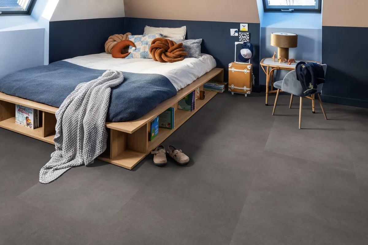 Peckham / Baroso grey, klik pvc in een slaapkamer onder een schuin dak, met een houten bedombouw en sloffen ervoor