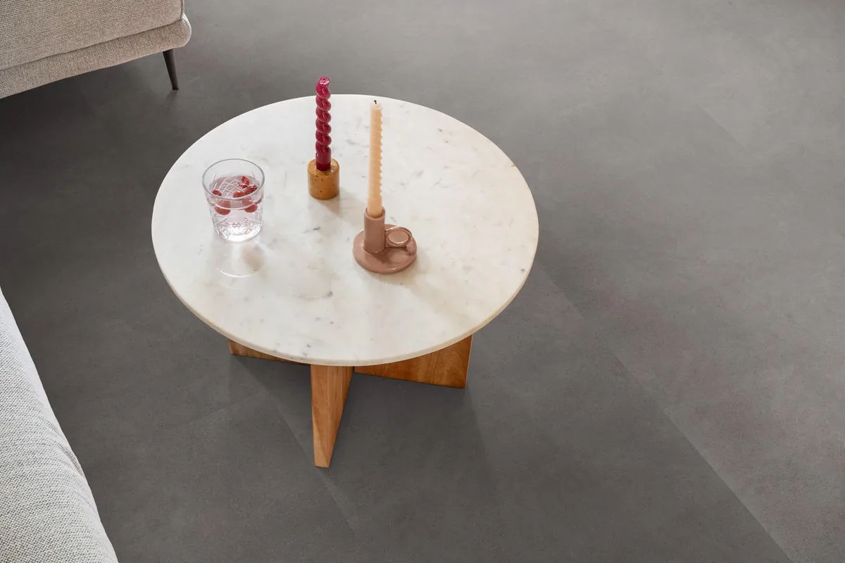 Peckham / Baroso grey, klik pvc in een woonkamer, met een ronde marmeren salontafel en twee kaarsen