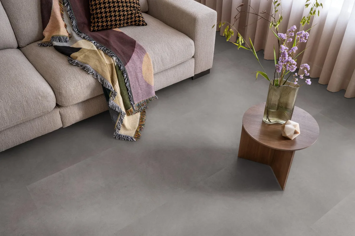 Peckham / Baroso grey, klik pvc in een woonkamer, met een beige bank en een ronde bijzettafel met bloemen