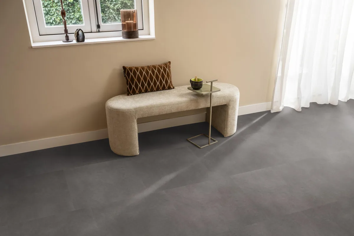 Peckham / Baroso grey, klik pvc in een hal, met een bankje onder het raam en zonlicht over de vloer