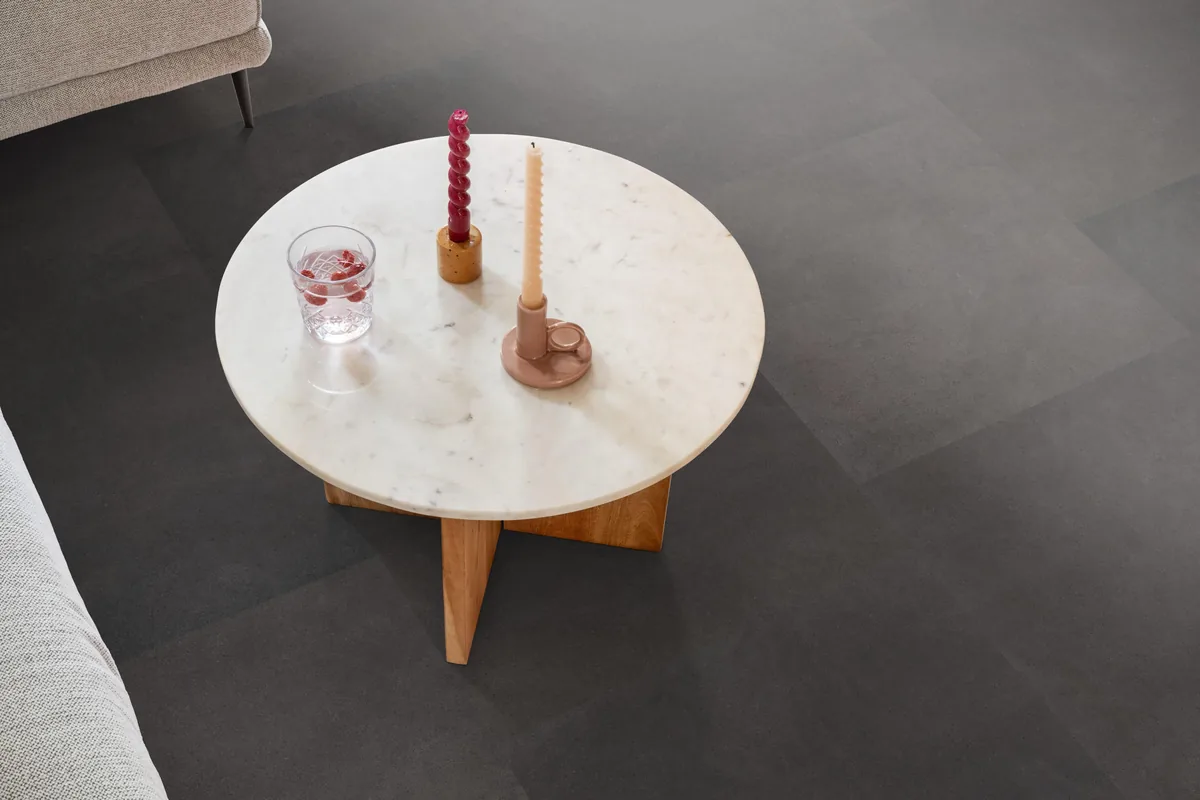 Peckham / Baroso anthracite, klik pvc in een woonkamer, met een ronde marmeren salontafel en twee kaarsen
