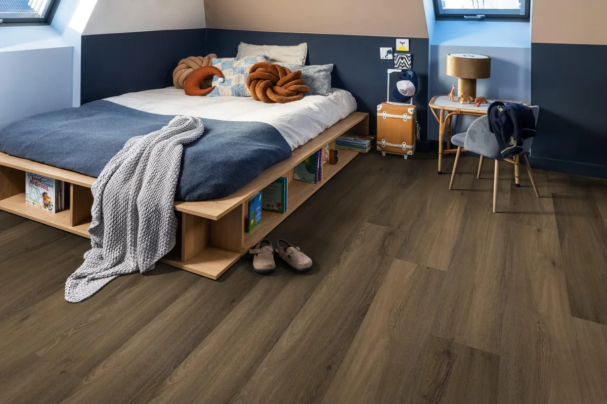 Paddington / Avanto Warm brown, klik pvc in een slaapkamer onder een schuin dak, met een houten bedombouw en sloffen ervoor