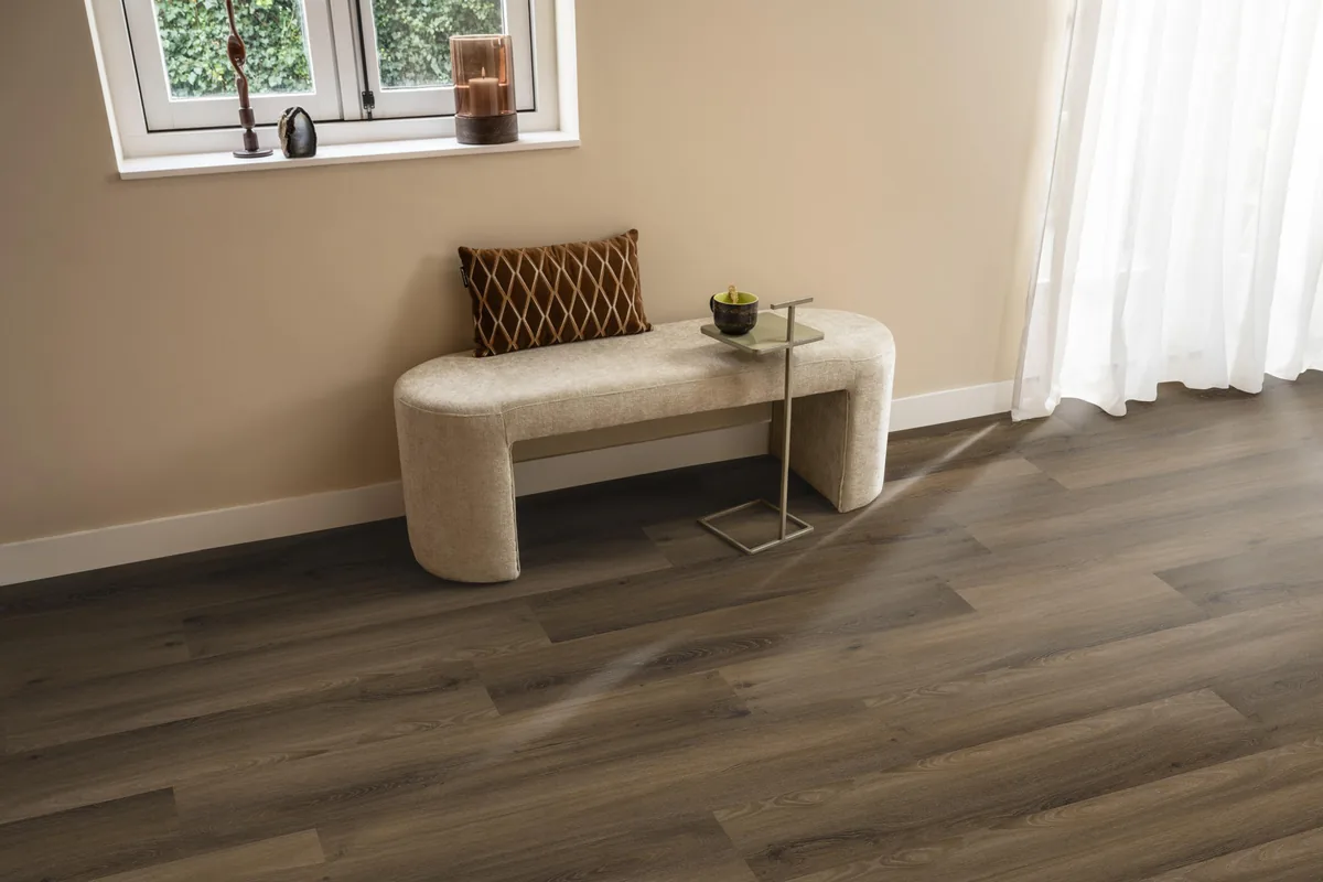 Paddington / Avanto Warm brown, klik pvc in een hal, met een bankje onder het raam en zonlicht over de vloer