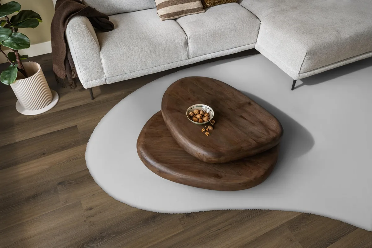 Paddington / Avanto Warm brown, klik pvc in een woonkamer, met een lichte hoekbank en een wit vloerkleed