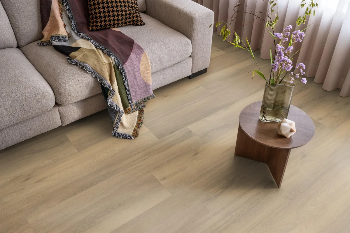 Paddington / Avanto natural, klik pvc in een woonkamer, met een beige bank en een ronde bijzettafel met bloemen