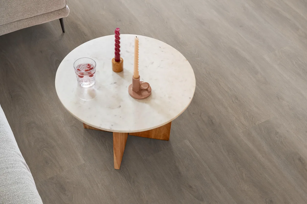 Parramatta / Robusto Smoky, klik pvc in een woonkamer, met een ronde marmeren salontafel en twee kaarsen