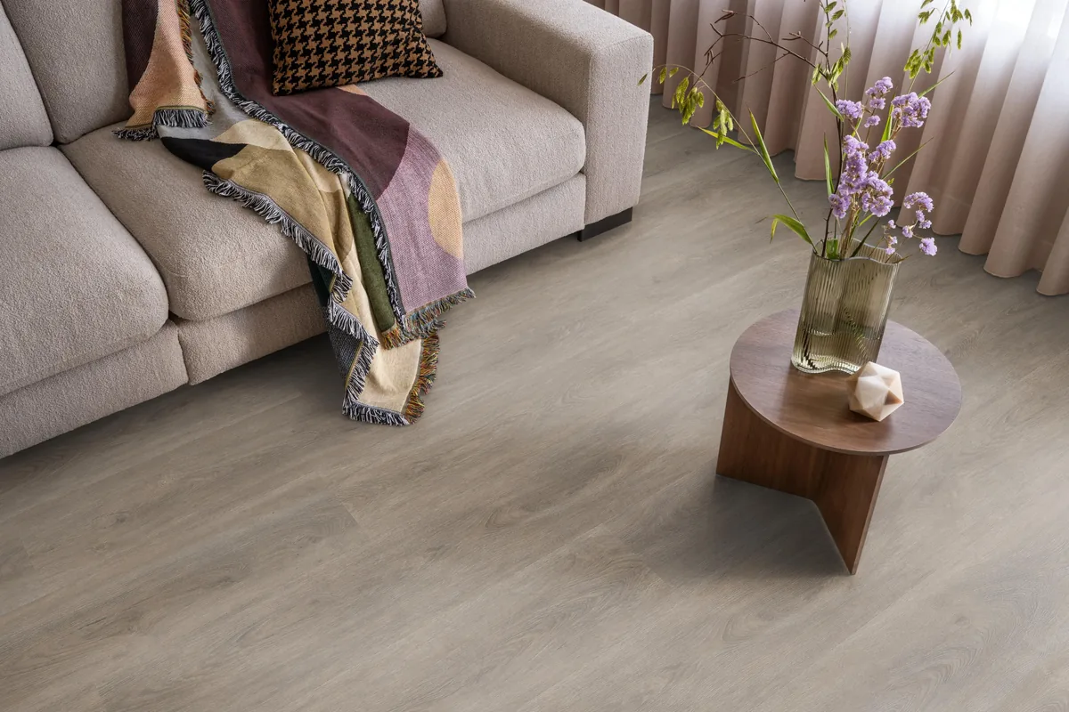Parramatta / Robusto Smoky, klik pvc in een woonkamer, met een beige bank en een ronde bijzettafel met bloemen