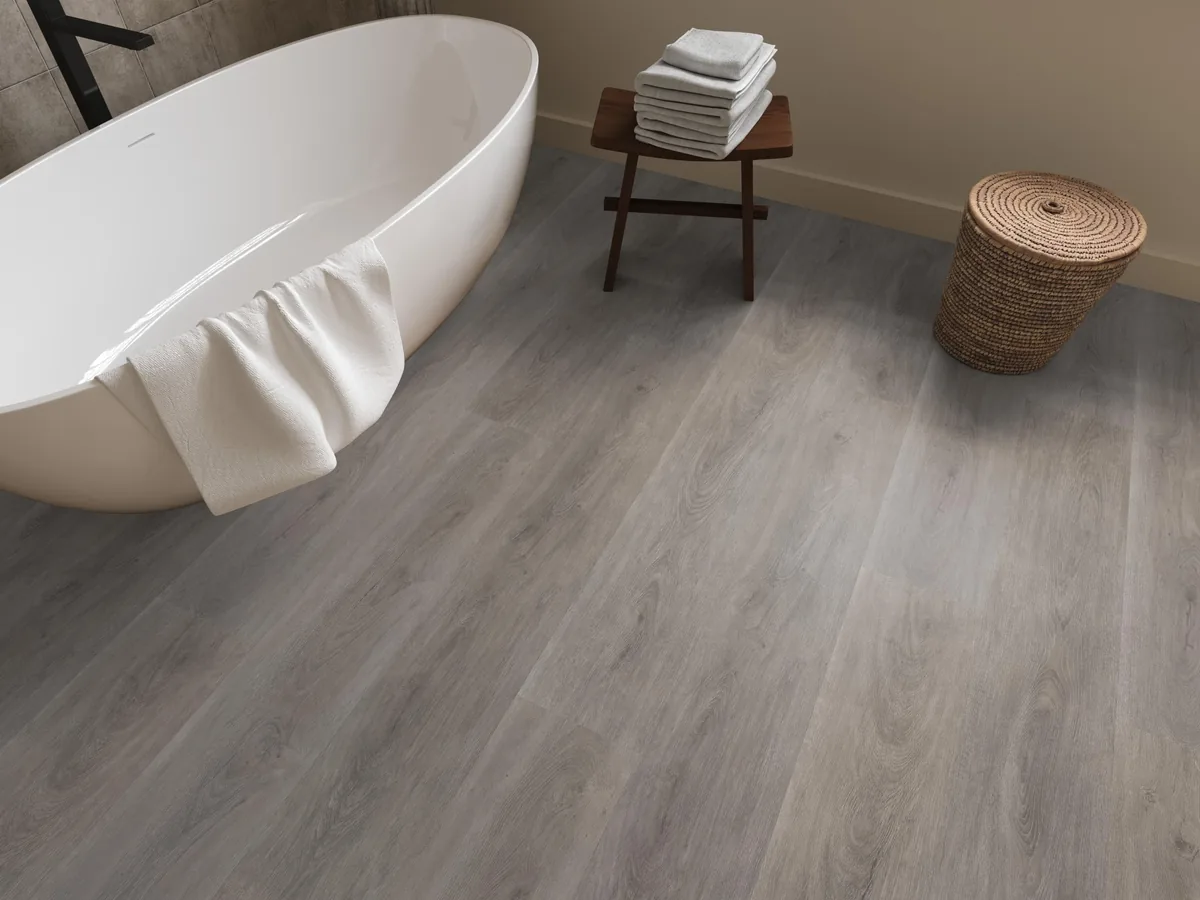 Parramatta / Robusto Grey oak, klik pvc in een badkamer, met een vrijstaand bad en een rieten wasmand